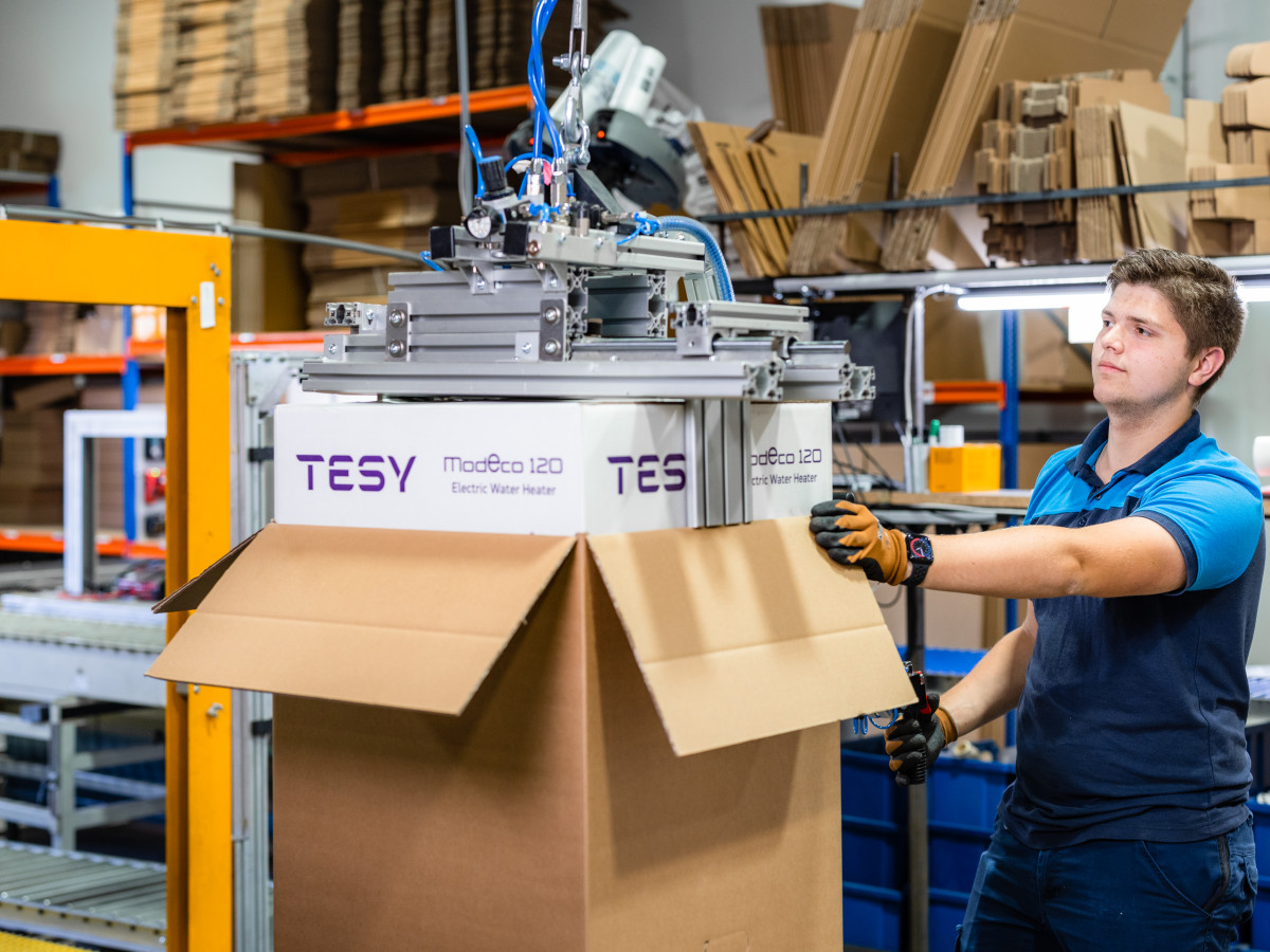 Tesy boiler inpakken in doos met behulp grijpautomaat door medewerker